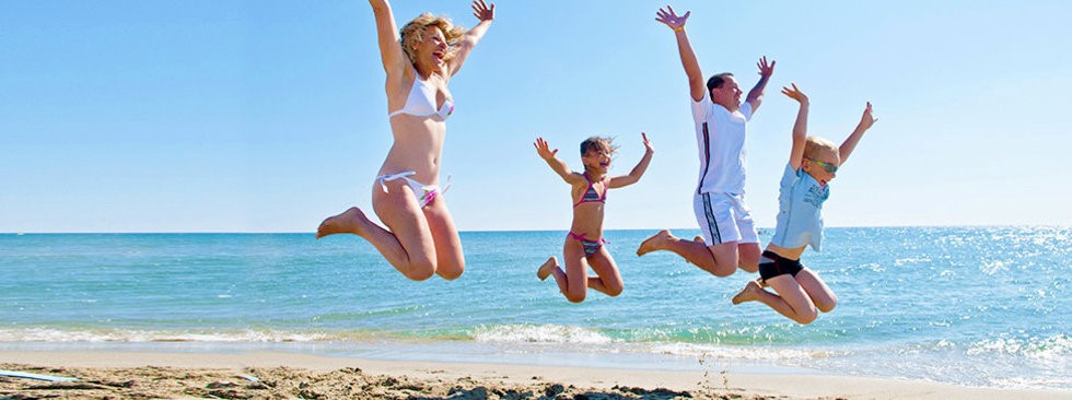 family jumping on beach on vacation